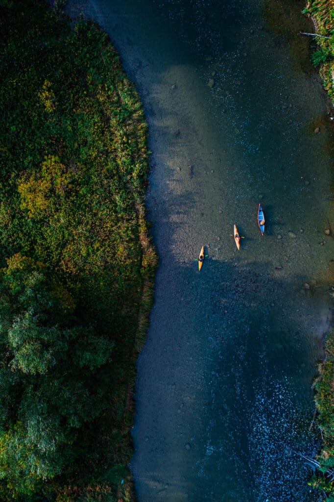 Aerial photo of a solo canoe and two kayaks navigating nith river