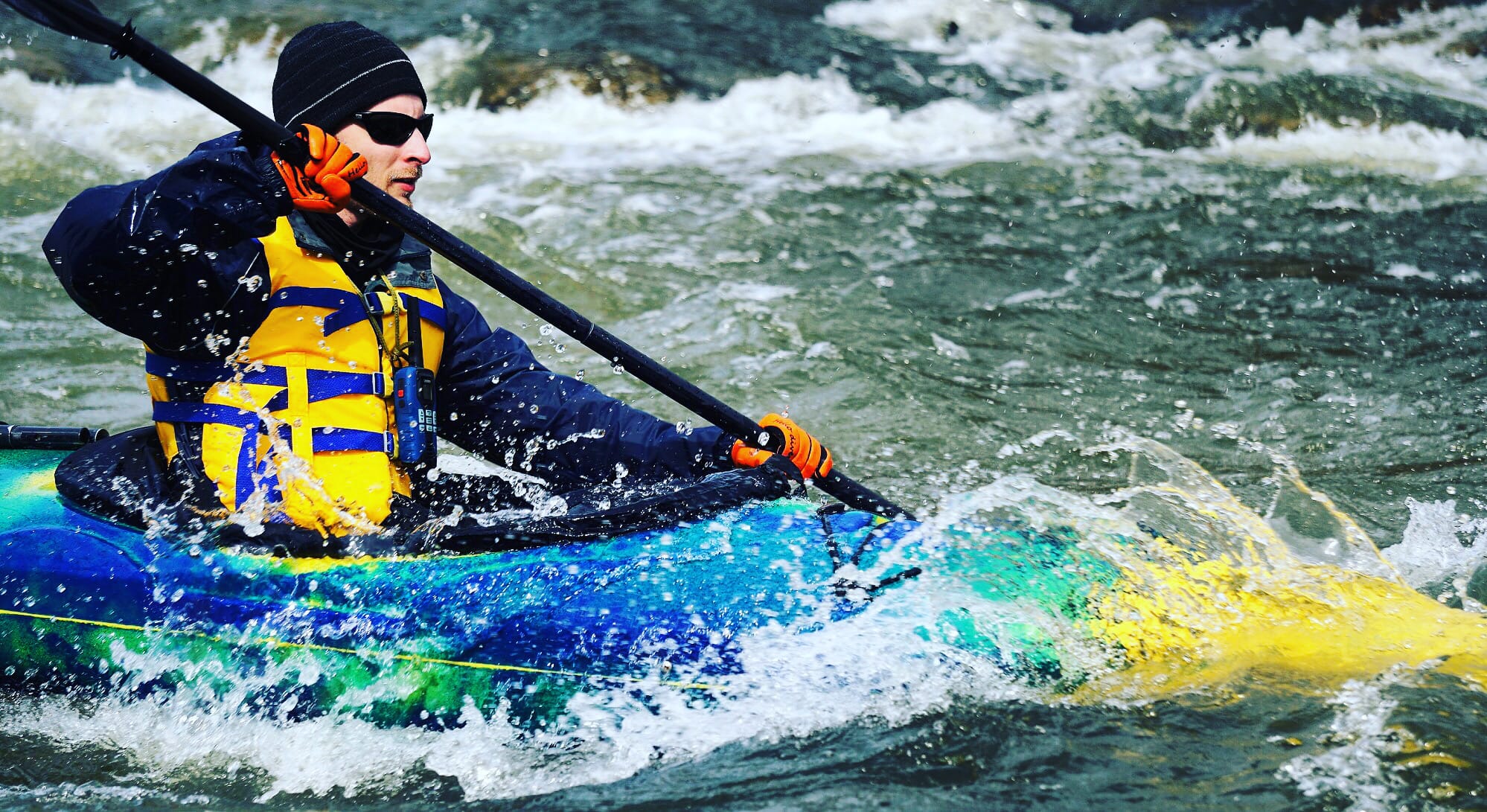 Man whitewater kayaking in a blue kayak