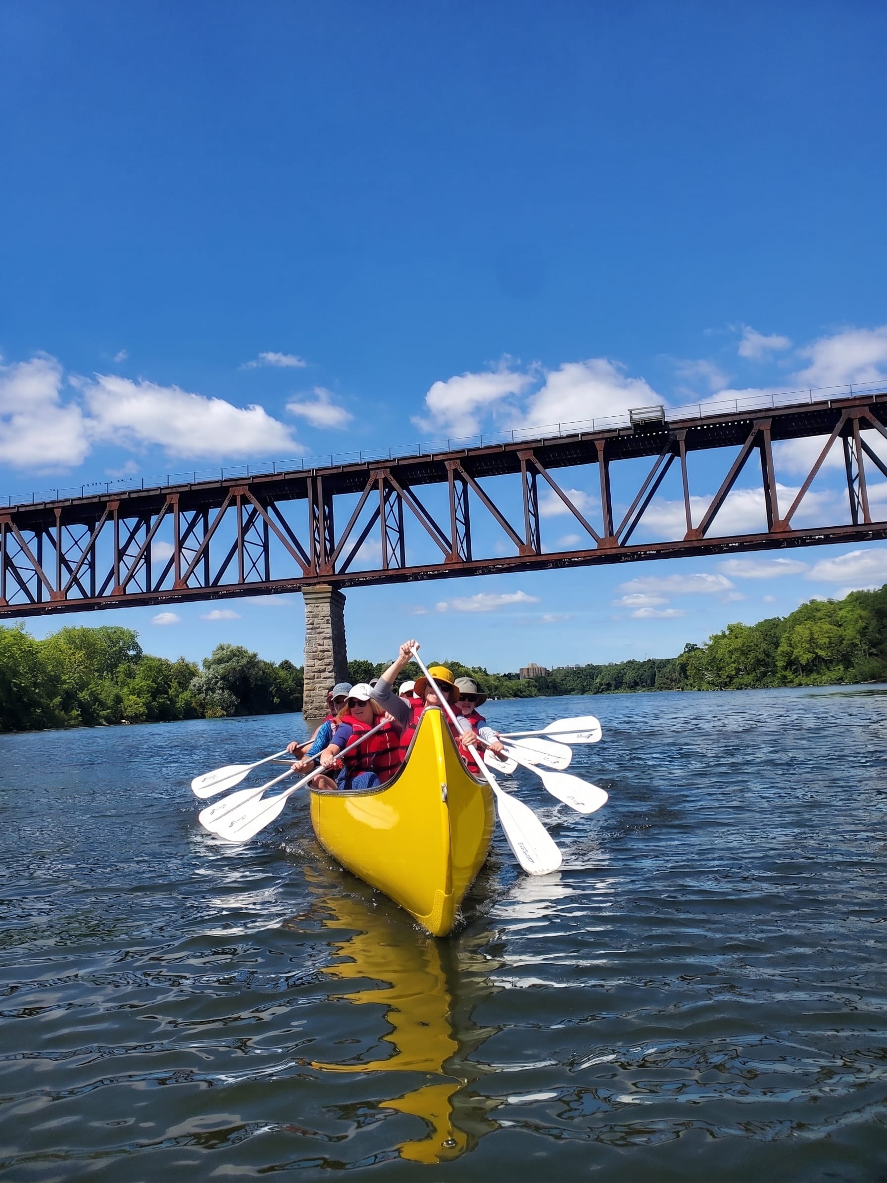 Updated voyageur canoes seniors group with train bridge in the background