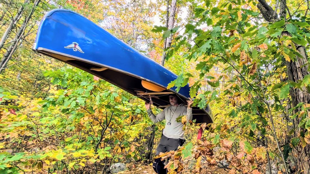 Portaging a blue canoe through crown lands
